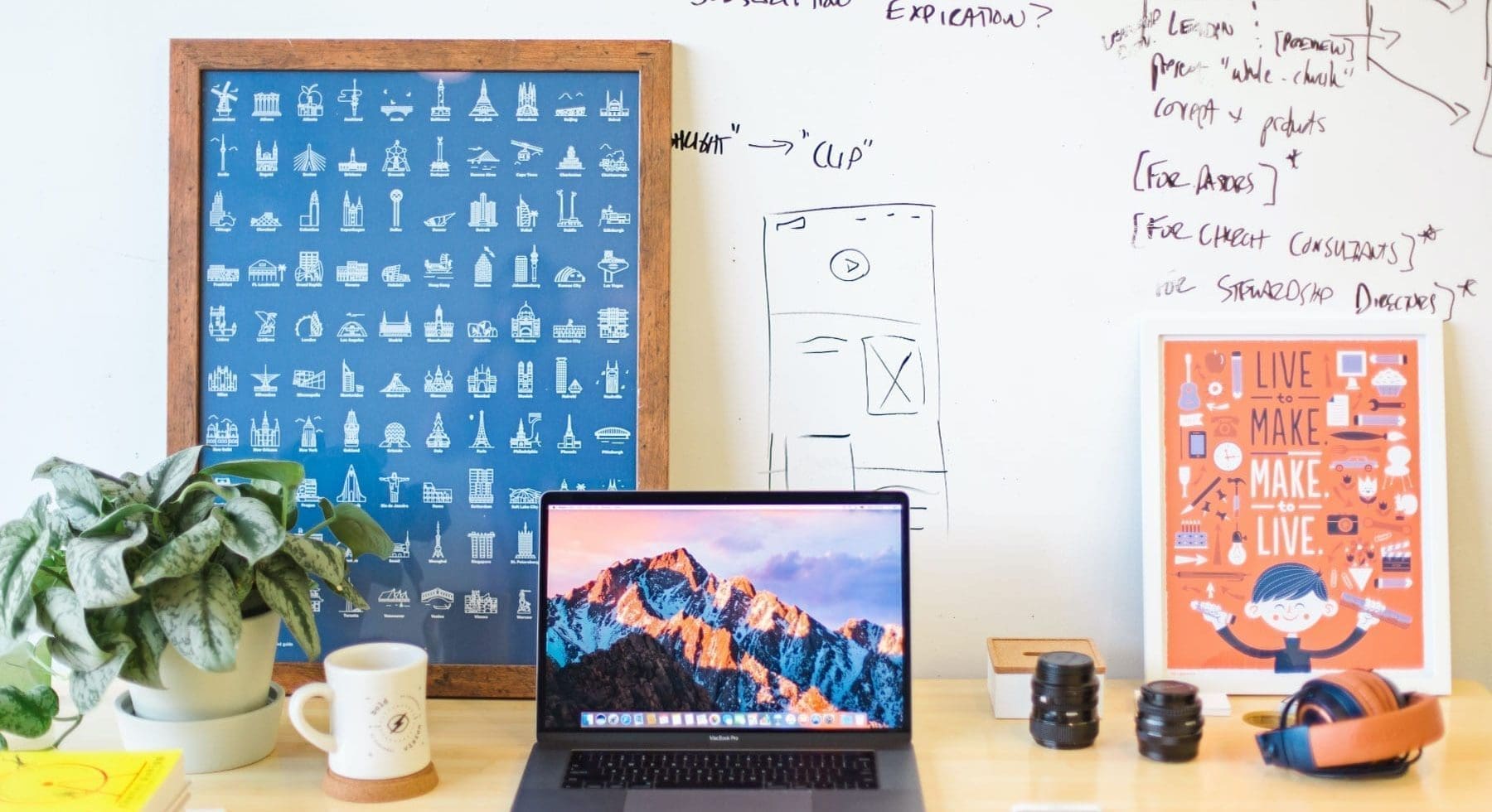 a workstation with laptop, plant, whiteboard
