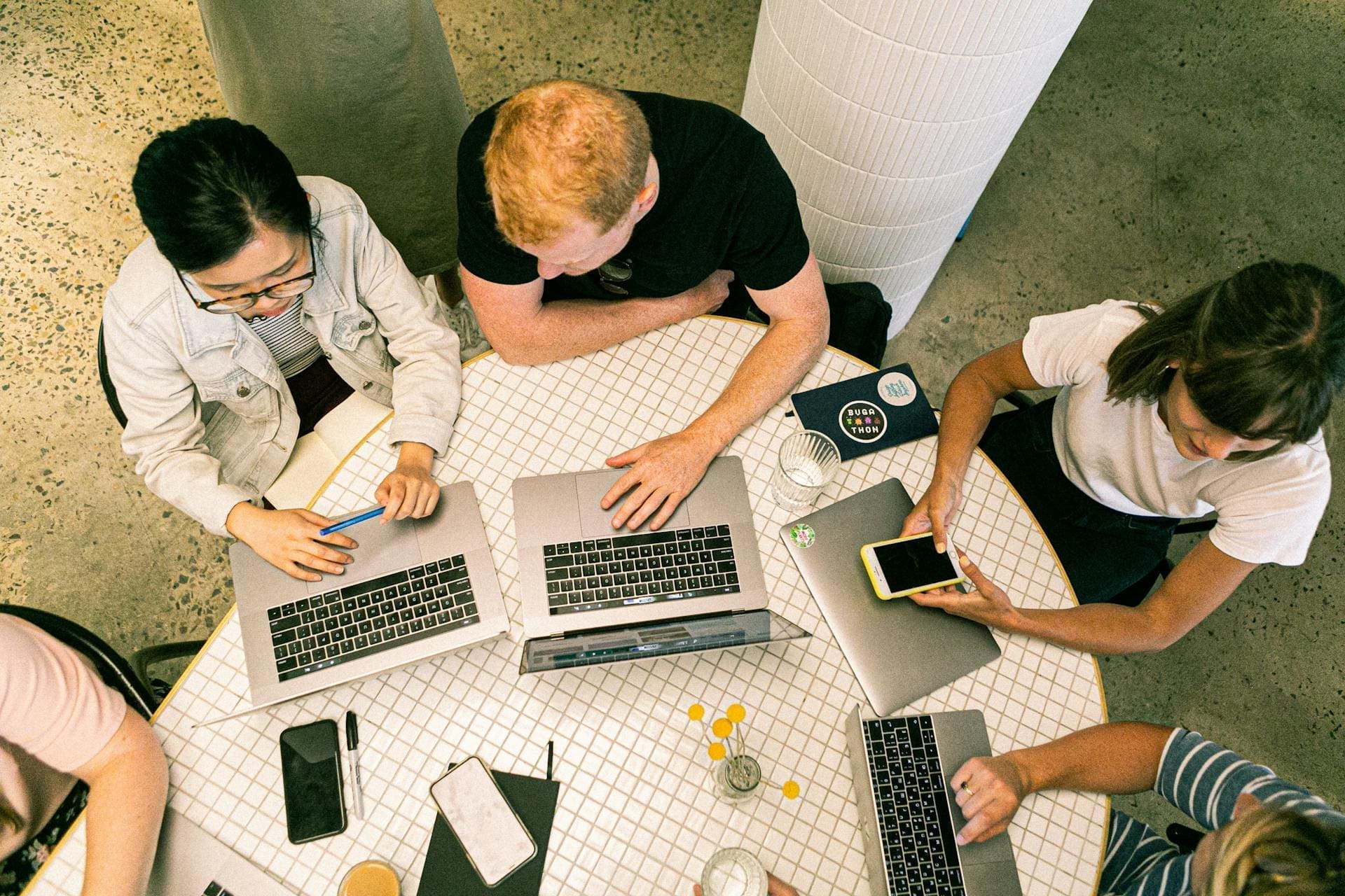 a group of people in a round table with laptops